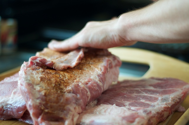 sprinkling dry rub on ribs